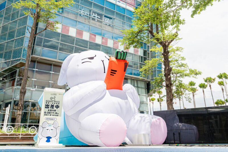 ▲抱著胡蘿蔔手機躺著耍廢的4米高布魯斯氣偶率先於水池廣場登場,展現厭世慵懶魅力。(圖/高雄夢時代提供)