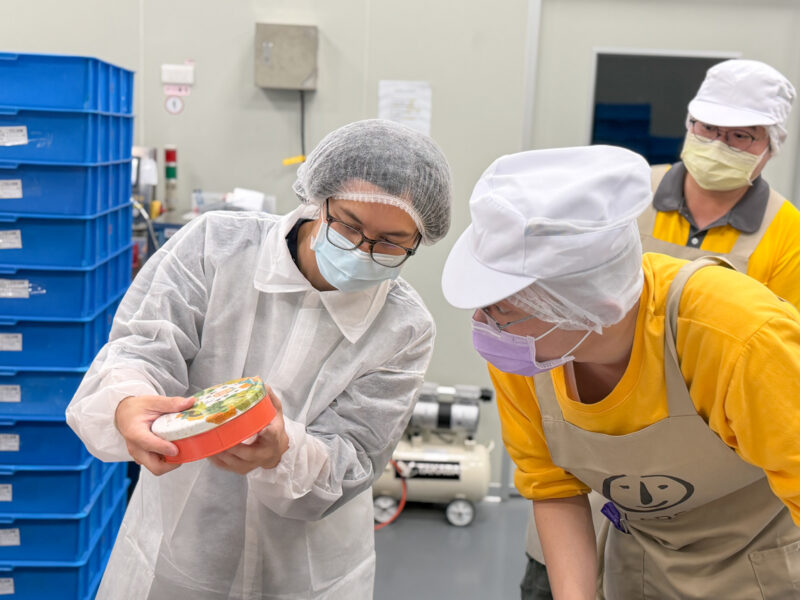 ▲ HowHow嘗試封裝餅乾盒，庇護員工阿宏檢查後直說「不行」。（圖/喜憨兒基金會提供）